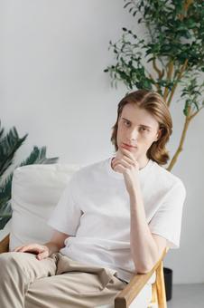 椅子に座る顎に手をやるカメラ目線の男性 男性,外国人,欧米人の写真素材