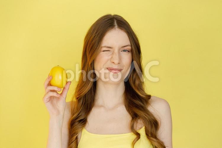 レモンを持ちウィンクする女性 女性,レモン,持つの写真素材