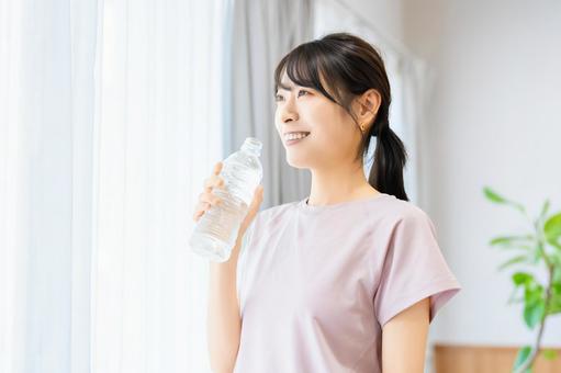 窓際でペットボトルの水を飲む女性 窓際でペットボトルの水を飲む女性 女性,リラックス,美容の写真素材
