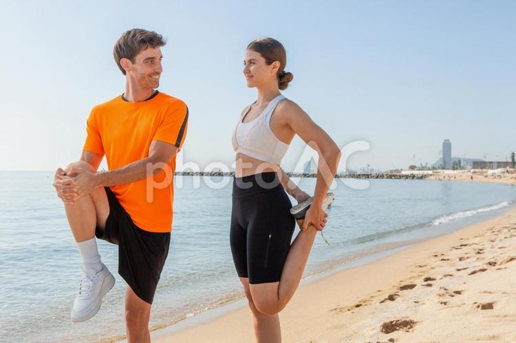 海辺で足のストレッチをする笑顔のカップル カップル,男女,男性の写真素材
