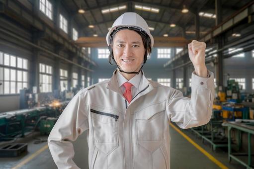 工場とガッツポーズする作業員 男性,作業服,ヘルメットの写真素材