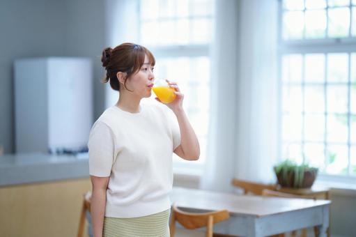 オレンジジュースを飲む女性の写真