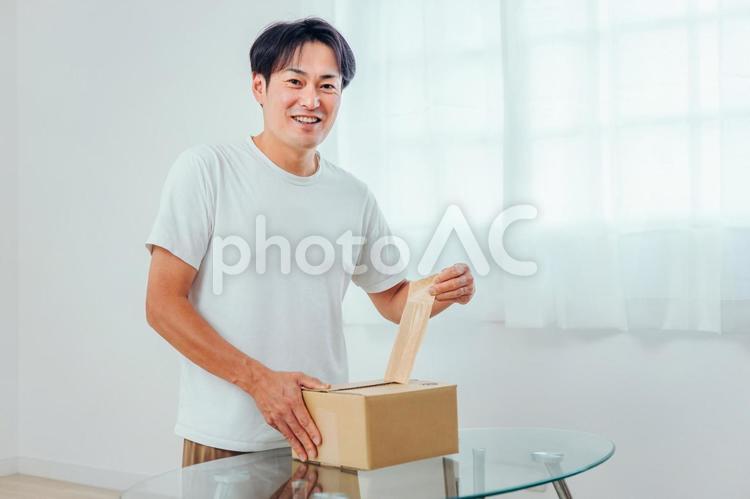 段ボールを開ける男性（笑顔） 荷造り,宅急便,宅配便の写真素材