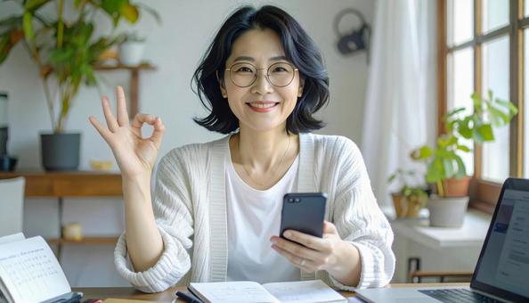 家計がうまくいきスマホ片手に微笑む女性 家計がうまくいきスマホ片手に微笑む女性の写真
