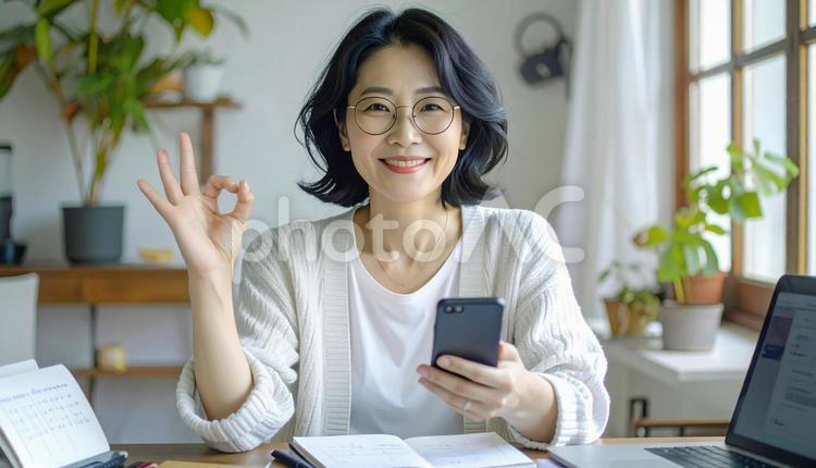 家計がうまくいきスマホ片手に微笑む女性 パソコン,家計簿,節約の写真素材