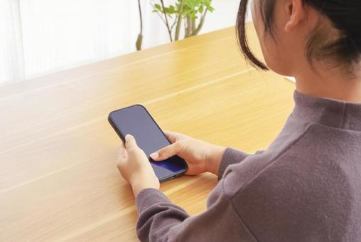 自宅でスマートフォンを使う女性 スマホ,スマートフォン,携帯電話の写真素材