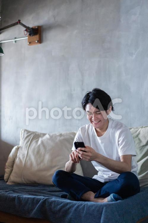 一人暮らしの家でスマホを使う若い男性 座って,ストレス解消,動画の写真素材
