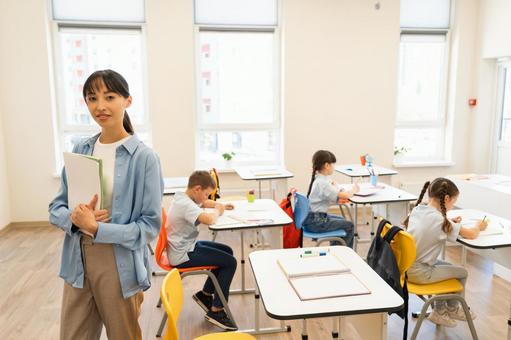 勉強する子どもたちとカメラ目線の先生 女性,女の子,男の子の写真素材