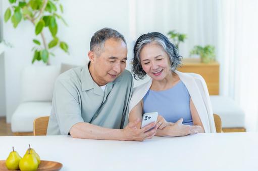 リビングでスマホを見るシニア夫婦 リビングでスマホを見るシニア夫婦 スマホ,笑顔,シニアの写真素材