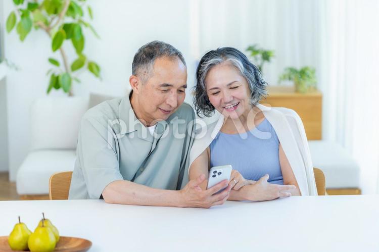 リビングでスマホを見るシニア夫婦 スマホ,笑顔,シニアの写真素材