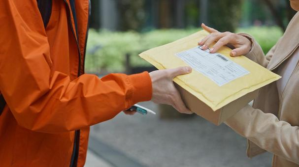 街なかで女性に配達物を渡す配達員 配達,デリバリー,配送の写真素材