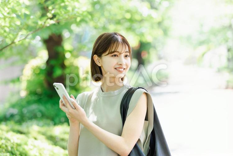 新緑の中、スマートフォンを使う若い女性 女性,人物,検索の写真素材