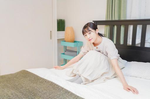 ベッドでリラックスをする若い女性 ベッドでリラックスをする若い女性 ワンルーム,ライフスタイル,白背景の写真素材