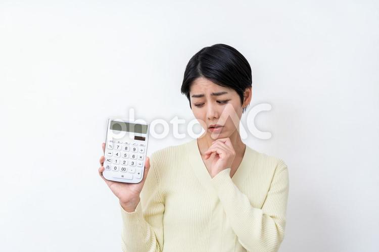 電卓を持って悩む主婦。 主婦,電卓,家計の写真素材