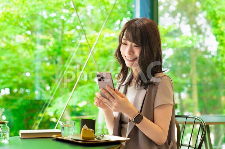 カフェでスマホを使う笑顔の女性 女性,カフェ,スマホの写真素材
