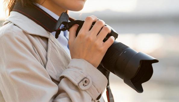 一眼レフを首から下げ手に取る女性 一眼レフを首から下げ手に取る女性の写真