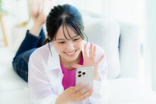 部屋でスマホを操作する若い女性 部屋でスマホを操作する若い女性 スマホ,若い女性,笑顔の写真素材