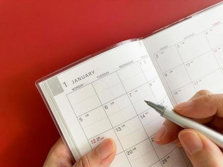1月のスケジュール帳に記入する女性の手 スケジュール帳,書く,手の写真素材