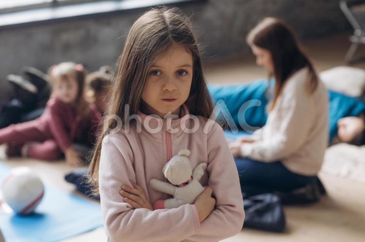 ぬいぐるみを抱きしめる女の子と後ろに女性と女の子たち 女の子,人物,抱きしめるの写真素材