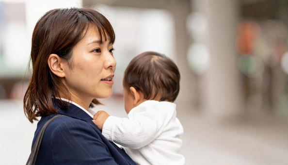 子供を抱っこして歩くシングルマザー 子供を抱っこして歩くシングルマザーの写真