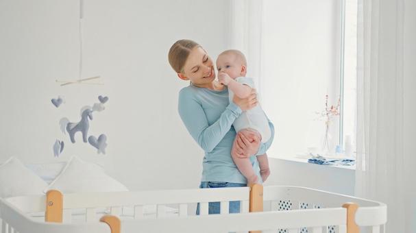 窓際で赤ちゃんを抱く笑顔の外国人女性 窓際で赤ちゃんを抱く笑顔の外国人女性 親子,抱っこ,赤ちゃんの写真素材