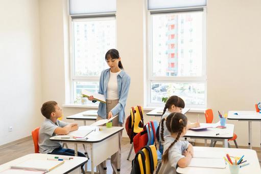 男の子に資料を配布する先生 女性,女の子,男の子の写真素材
