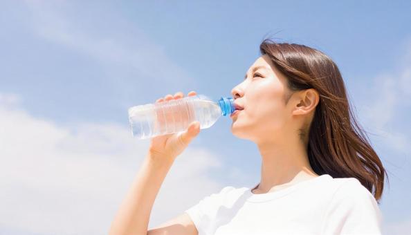 水分補給をするTシャツの女性 水分補給をするTシャツの女性の写真