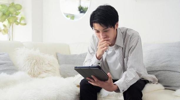 深刻な表情でニュースをみるアジア人男性 深刻な表情でニュースをみるアジア人男性 男性,ニュース,タブレットの写真素材