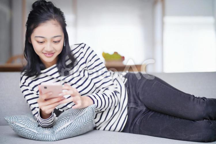 横になりスマホを操作する女性 女性,寛ぐ,日本人の写真素材