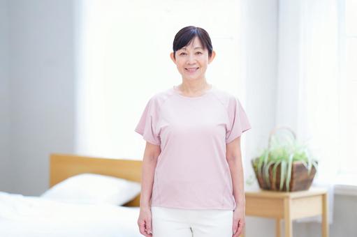明るい部屋で微笑むピンクの服の中年女性 明るい部屋で微笑むピンクの服の中年女性 主婦,シニア,立ち姿の写真素材