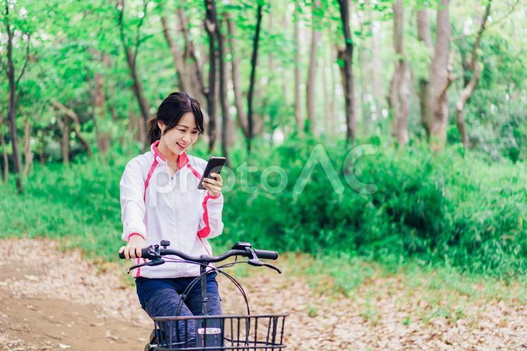 自転車に乗りながらスマホを使う女性 メール,危険,目的地の写真素材