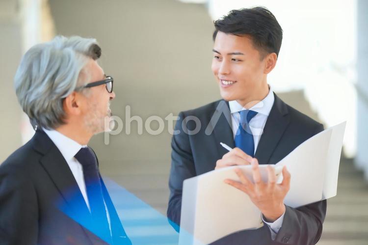 ノートに書きながら話をするビジネスマン ビジネスマン,日本人,会社員の写真素材