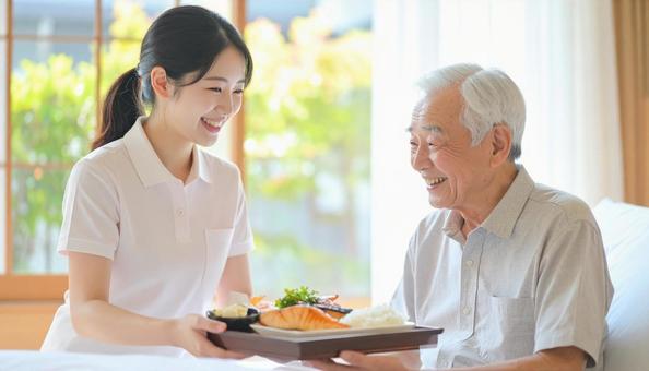 高齢男性と女性介護士の穏やかな食事風景の写真