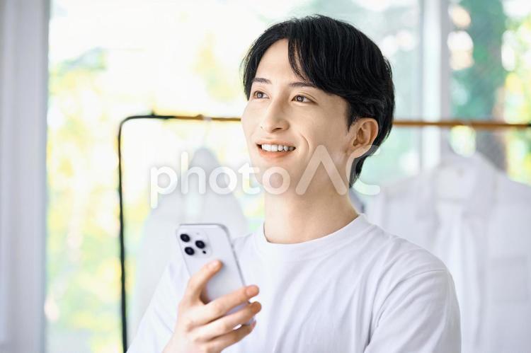 スマホを持つ若い男性　自宅　リビング 男性,スマホ,一人暮らしの写真素材