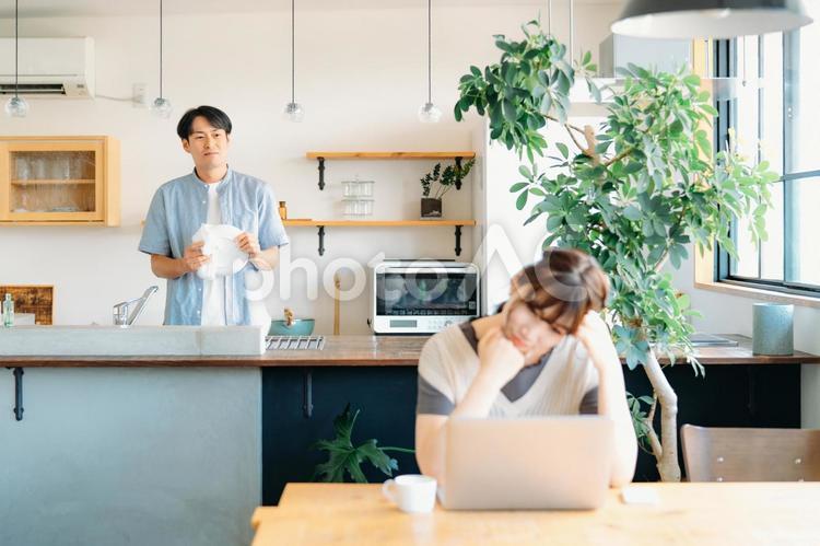 仕事で疲労する女性と家事をする男性（心配） 主夫,共働き,心配の写真素材