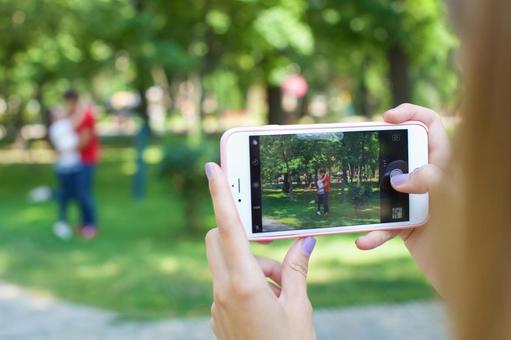 A woman taking a picture of a love couple in the park 7, take a picture, smartphone, summer, JPG