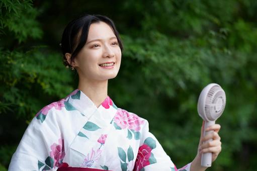 浴衣姿の女性がハンディファンを持って微笑む 女性,浴衣,ハンディファンの写真素材