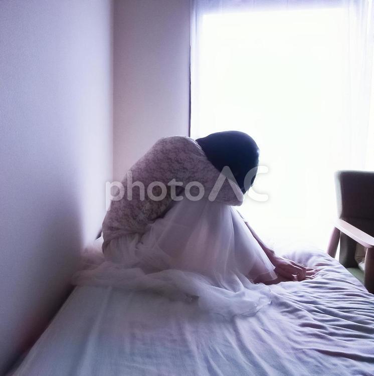 ベッドの上でうずくまる女性 女性,休む,悩むの写真素材