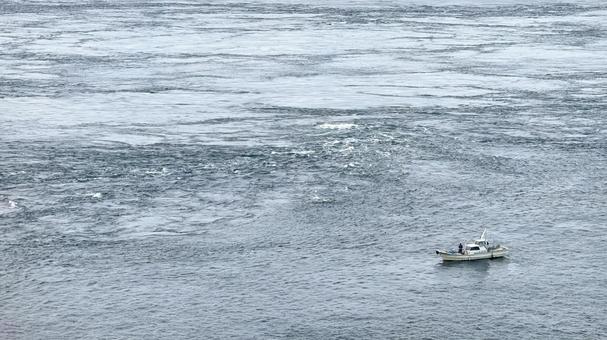 広大な海に浮かぶ小型漁船と潮のうねり 海,漁船,潮流の写真素材