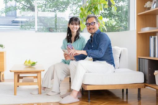 リビングでスマホを見るミドルの夫婦 夫婦,家族,ミドルの写真素材