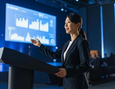 スクリーンの前でプレゼンする女性 スクリーンの前でプレゼンする女性の写真