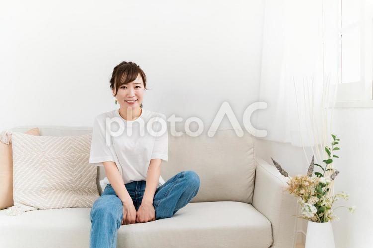 家のソファに座る笑顔の日本人女性 女性,笑顔,ソファの写真素材