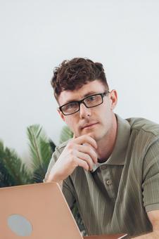 椅子に座って手に持ってノートパソコンを使う筋肉質な男性 男性,外国人,欧米人の写真素材