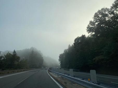 早朝の霧と朝焼けの高速道路の写真