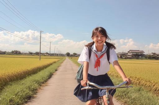 田んぼのあぜ道を自転車で走る女子高生 田んぼのあぜ道を自転車で走る女子高生の写真