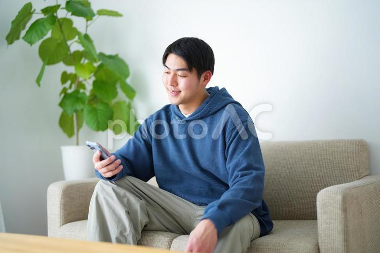 ソファに座ってスマートフォンを見ている男性 引っ越し,一人暮らし,男性の写真素材