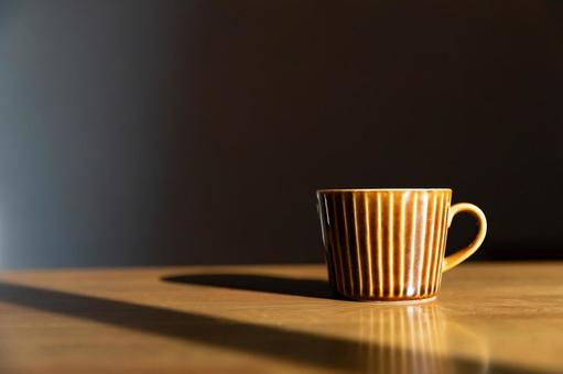 朝日を浴びるコーヒーカップと黒背景 朝日を浴びるコーヒーカップと黒背景の写真