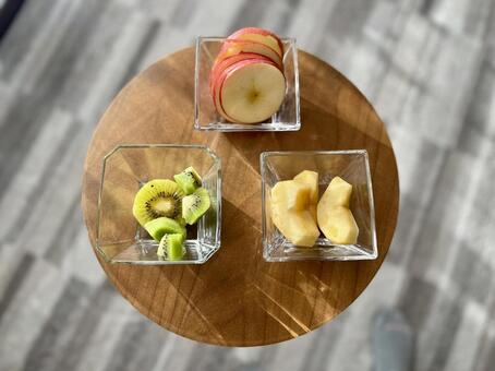 丸テーブルに乗ったフルーツ フルーツ,木製テーブル,ガラスの器の写真素材