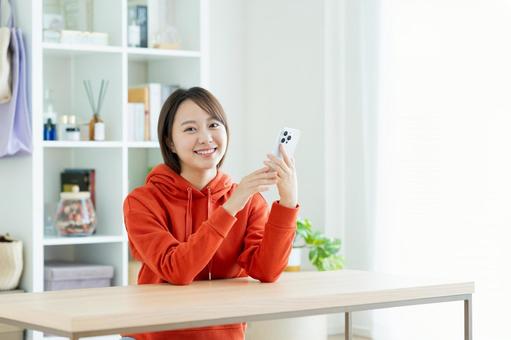 リビングでスマホを使う若い女性 リビングでスマホを使う若い女性 スマホ,女性,家の写真素材