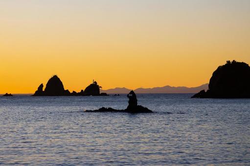 夕焼けに染まる空とゴジラ岩のシルエット 夕焼け,ゴジラ岩,シルエットの写真素材